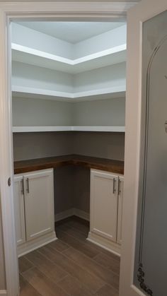 an empty room with white cabinets and wood flooring in the corner between two closets