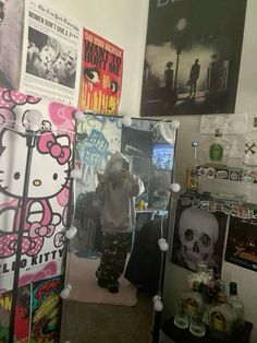 a person taking a selfie in a mirror with hello kitty posters on the wall