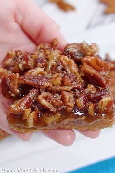 a hand holding a piece of pecan bar in it's left hand, with the rest of the bar partially eaten