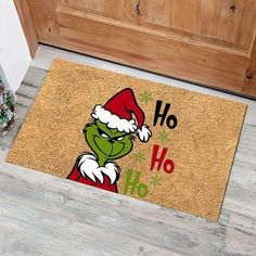 the grinch door mat is on the floor next to a potted plant and christmas tree