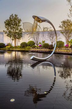 a large metal sculpture sitting in the middle of a pond