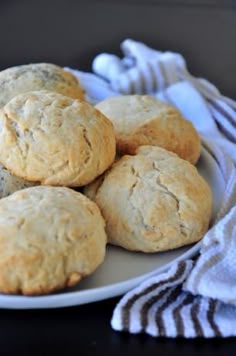 a white plate topped with muffins on top of a table next to a towel