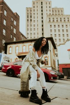 a woman sitting on top of a skateboard next to tall buildings in the city