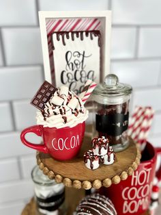 hot chocolate and marshmallows in a red cup on a wooden tray with candy canes