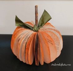 an origami pumpkin made out of books with a green ribbon on the top