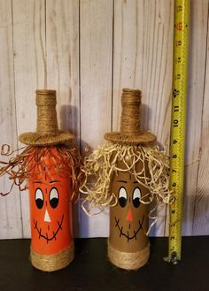 two pumpkins with faces painted on them are sitting next to a ruler and rope