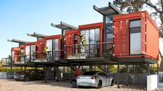 two cars are parked in front of three red shipping containers on top of each other