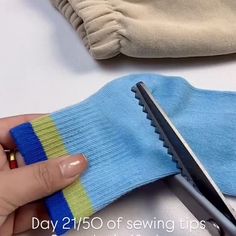 someone is using scissors to cut the fabric off of a pair of blue and green socks