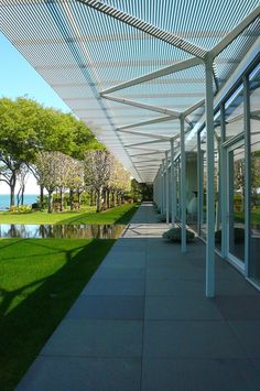 the walkway is lined with glass doors leading to an outdoor area that has water and trees on both sides