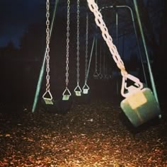 an empty swing set at night with no one on the swings or in the ground