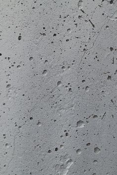 drops of water on the surface of a concrete wall, with small holes in it