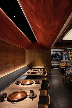 an empty restaurant with wooden tables and plates on the long table, along with other dining room furniture