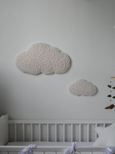 two white clouds hanging on the wall above a crib