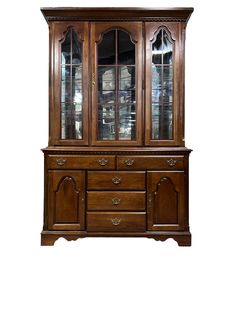 a wooden china cabinet with glass doors on the top and bottom drawers, in front of a white background