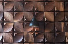 a wall made out of wooden blocks with a light hanging from the ceiling in front of it