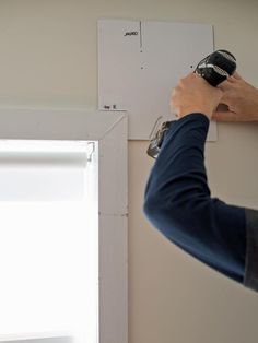 a person using a paint roller to paint a wall with white paint on the walls