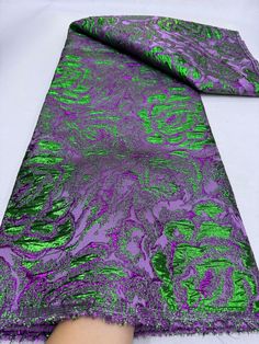 a purple and green tie laying on top of a white table next to a person's hand