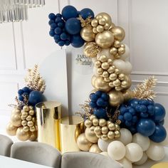 a table topped with balloons and blue, gold and white decorations on top of it