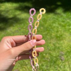 a hand is holding some colorful beads in the grass and it looks like they are made out of yarn