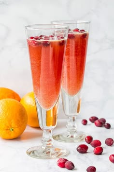 two glasses filled with cranberry wine next to oranges