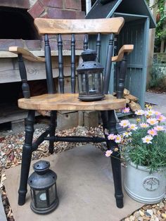 an old chair with a lantern on it and some flowers in the potted planter