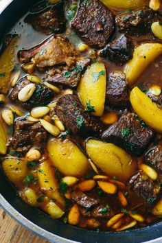 a pot filled with stew and potatoes on top of a wooden table