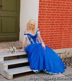 a woman in a blue dress sitting on steps