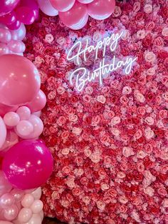 pink and white balloons are in front of a wall with the words happy birthday written on it