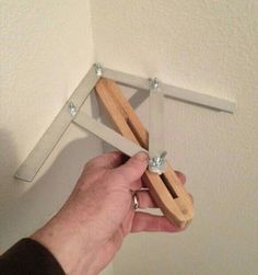 a hand holding a pair of scissors in front of a wall mounted hook on the ceiling