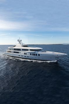 a large white boat in the middle of the ocean with blue sky and clouds behind it