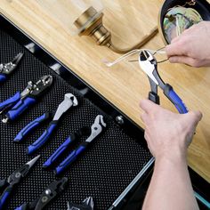 a person is holding pliers in front of some tools on a table with other tools