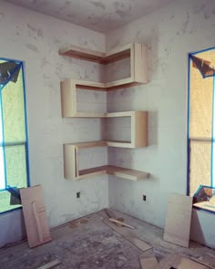 an empty room with unfinished shelves in the middle and two windows on the other side