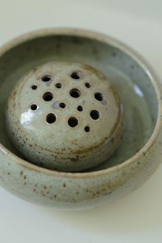 a ceramic bowl with holes in it on a table