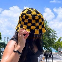 a woman wearing a black and yellow crocheted hat holding up a piece of string