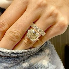 a woman's hand with two engagement rings on top of her finger and the other hand holding an engagement ring