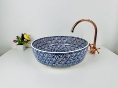 a blue and white bowl sink sitting on top of a counter next to a faucet