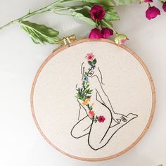 a cross - stitch embroidery with a woman's body and flowers on the hoop