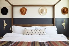 a bed with two hats mounted on the wall above it and pillows in front of it