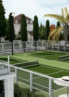 a tennis court surrounded by palm trees and white fenced in area with green grass