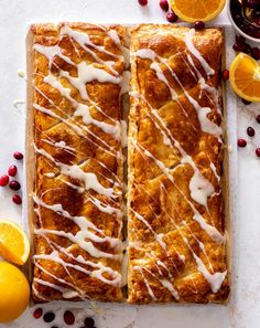 two slices of orange cranberry bread on a cutting board next to sliced oranges