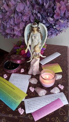 an angel figurine sitting on top of a table next to paper and candles