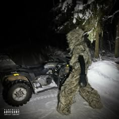 a man in camouflage walking next to a four - wheeler on the snow at night