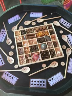 a tray with many different types of buttons and wooden utensils in them on a table