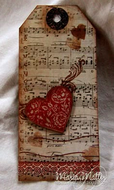 a red heart with music notes on it sitting on top of a sheet of paper