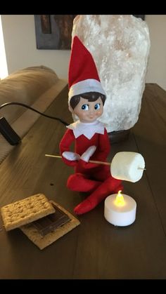 an elf is sitting on the table with marshmallows