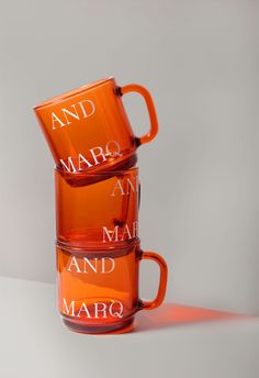 two orange coffee mugs with the words and marq on them sitting side by side