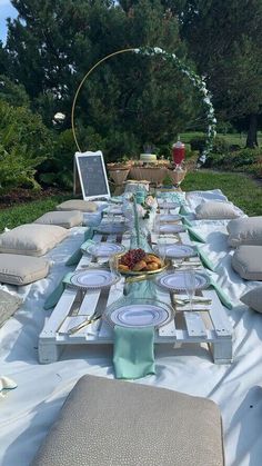 a long table set up with plates and place settings for an outdoor dinner in the garden