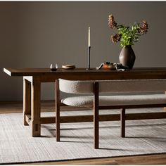 a wooden table sitting on top of a rug next to a vase filled with flowers