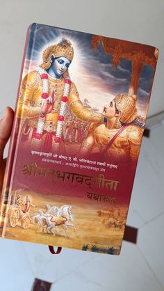 a person holding up a book with an image of lord and goddess on the cover