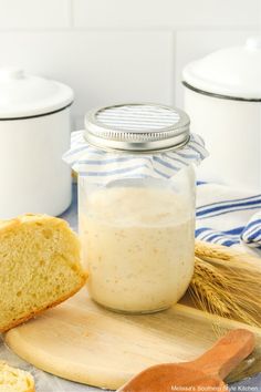 a loaf of bread sitting on top of a wooden cutting board next to a jar